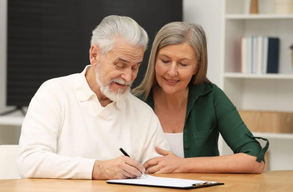 A senior with dementia signing a document that grants power of attorney.