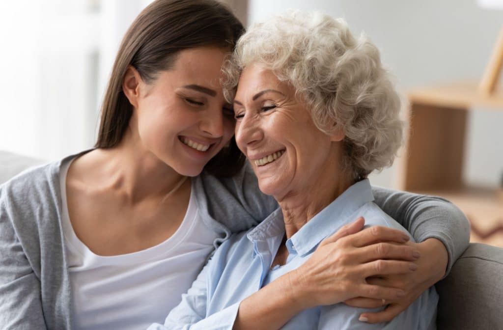 A daughter hugs her mature parent in memory care.