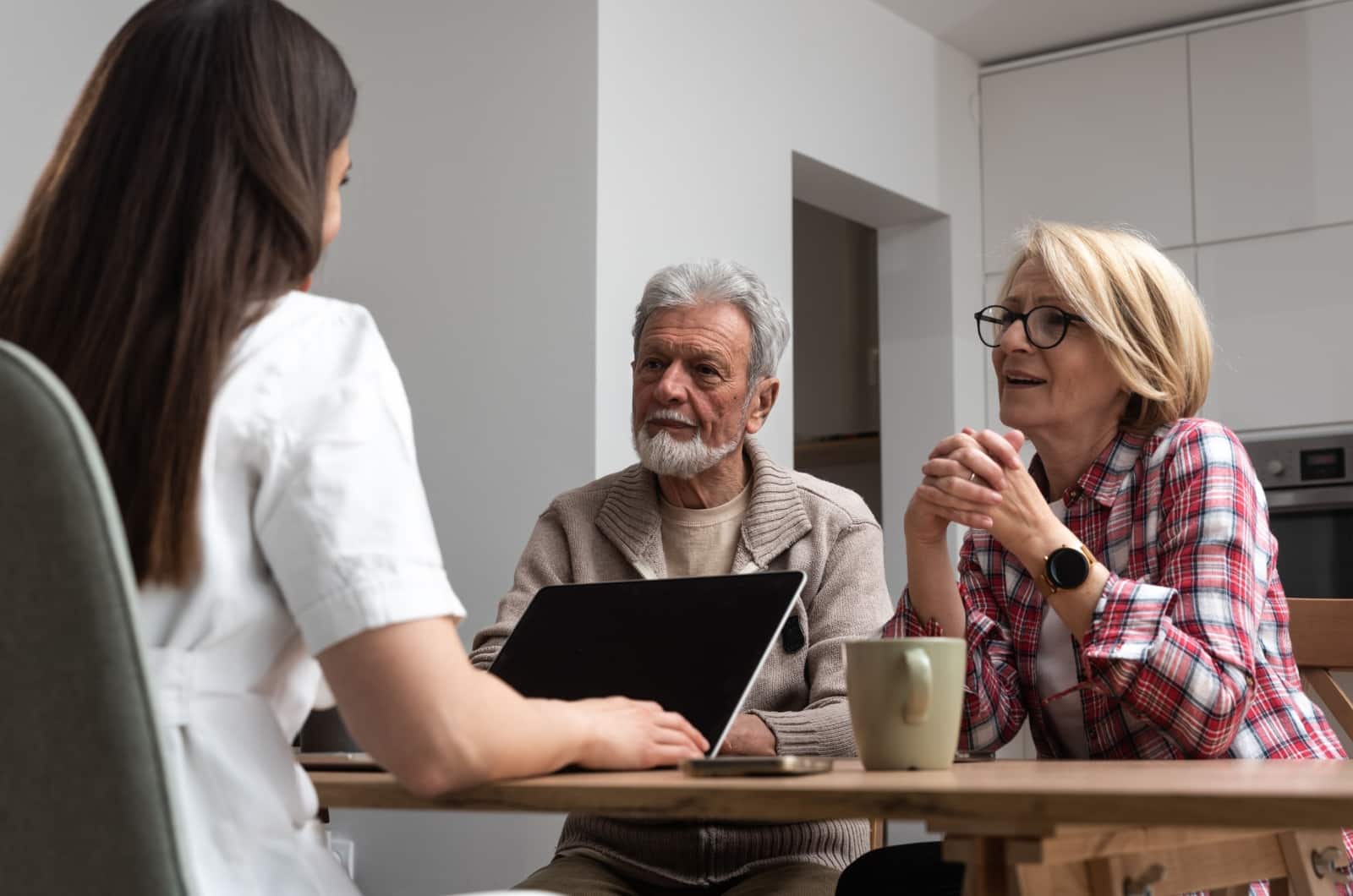 An older couple and healthcare worker sitting at a table discussing assisted living.