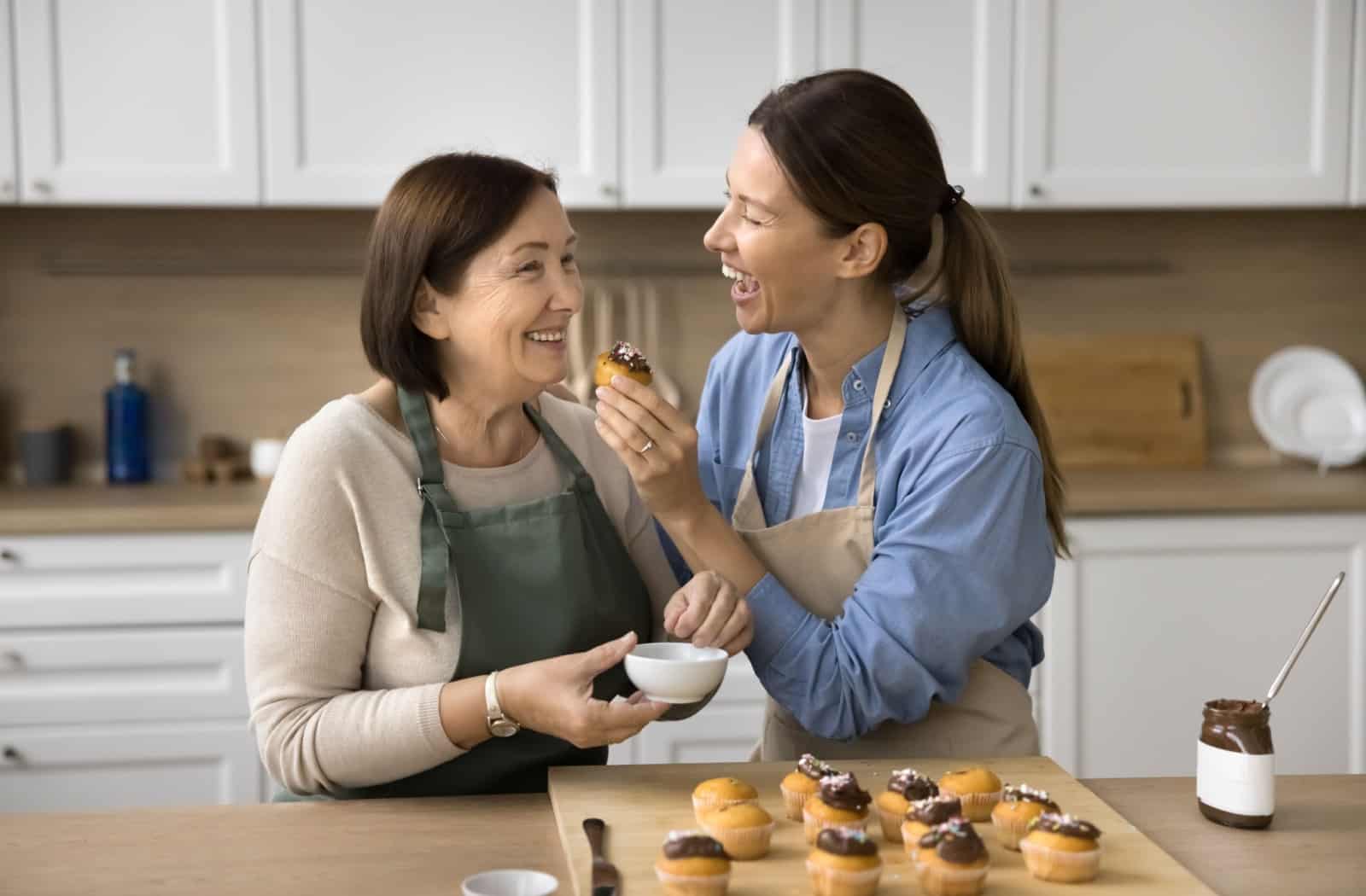 An adult child joyfully bakes with their parent who has early-stage dementia.